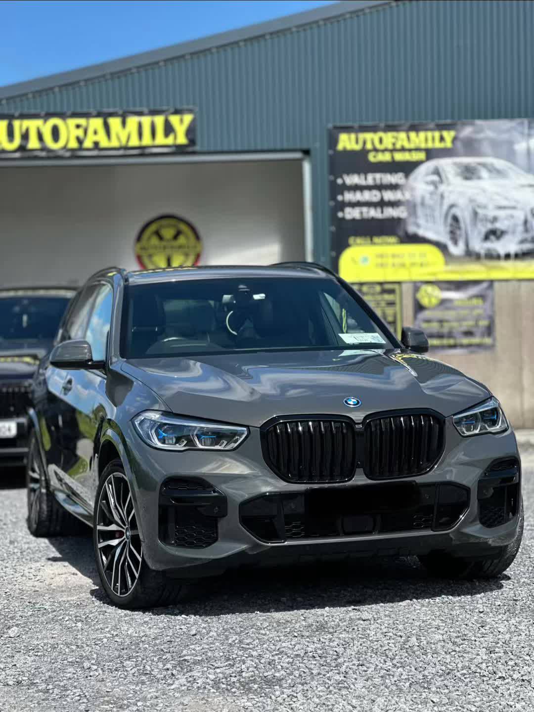 A grey BMW SUV parked in front of a car wash facility.