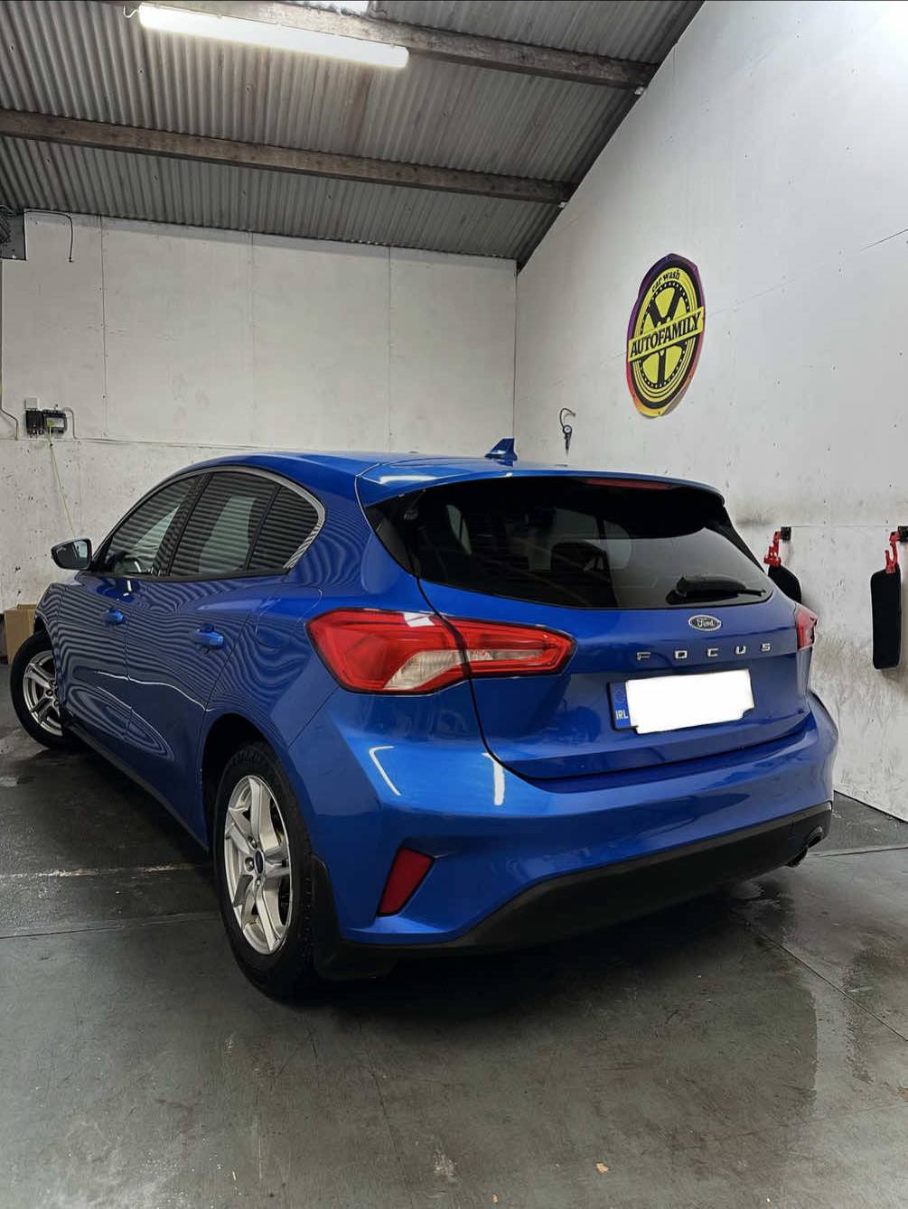 Blue Ford Focus parked inside a clean car valeting bay.