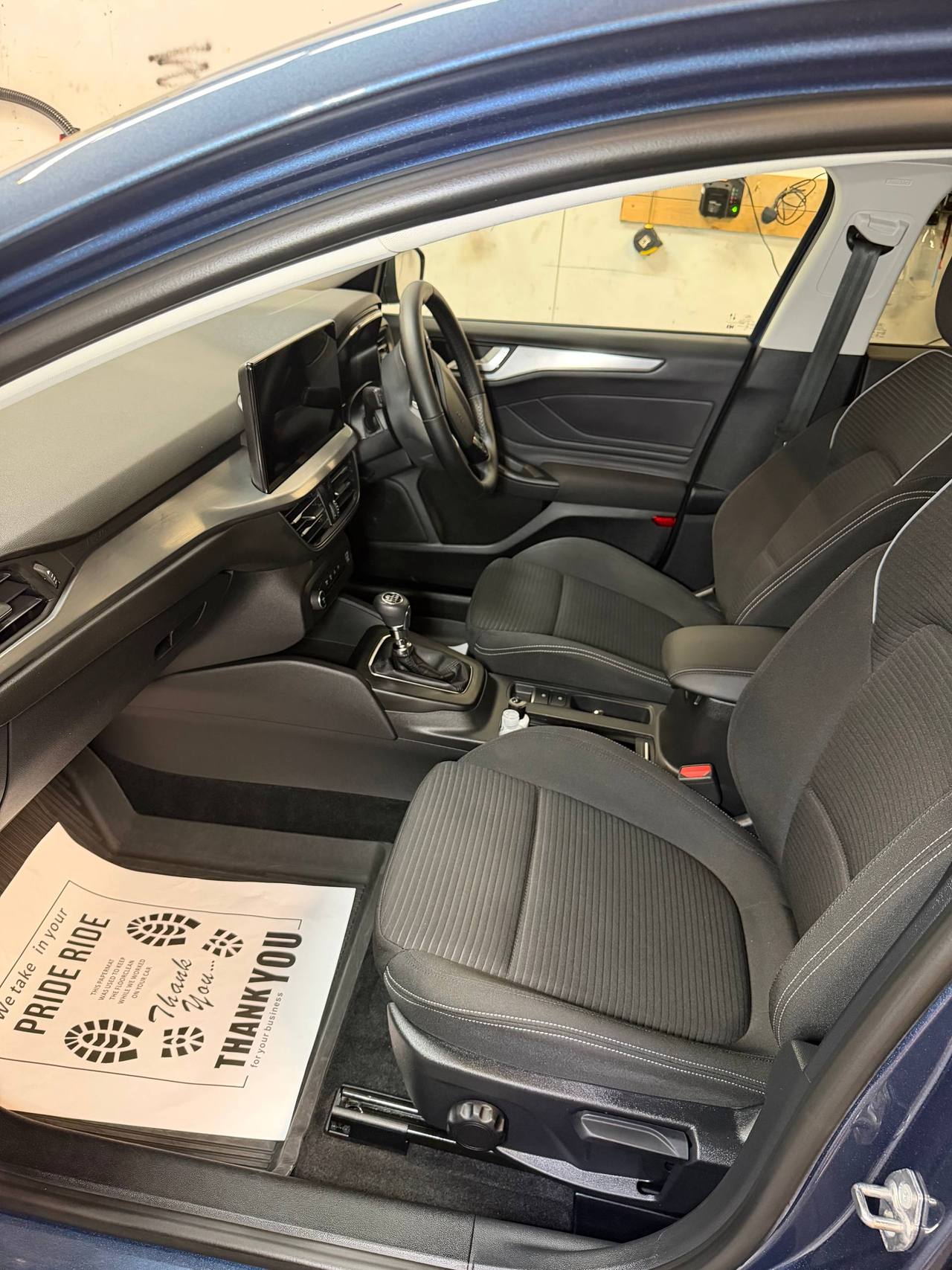 Car interior with black textured seats and steering wheel visible through open door