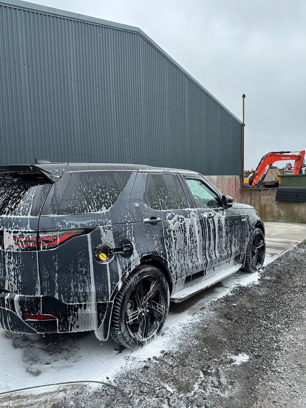 Dark SUV covered in soapy water during professional wash